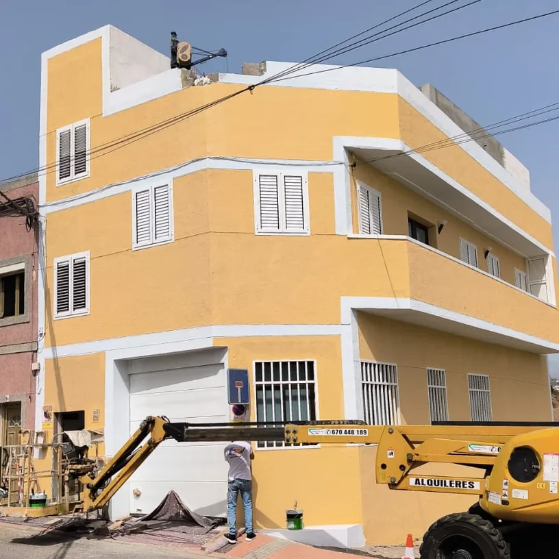 El mismo edificio de esquina terminado en amarillo con cornisas y recercados en blanco, en Gran Canaria